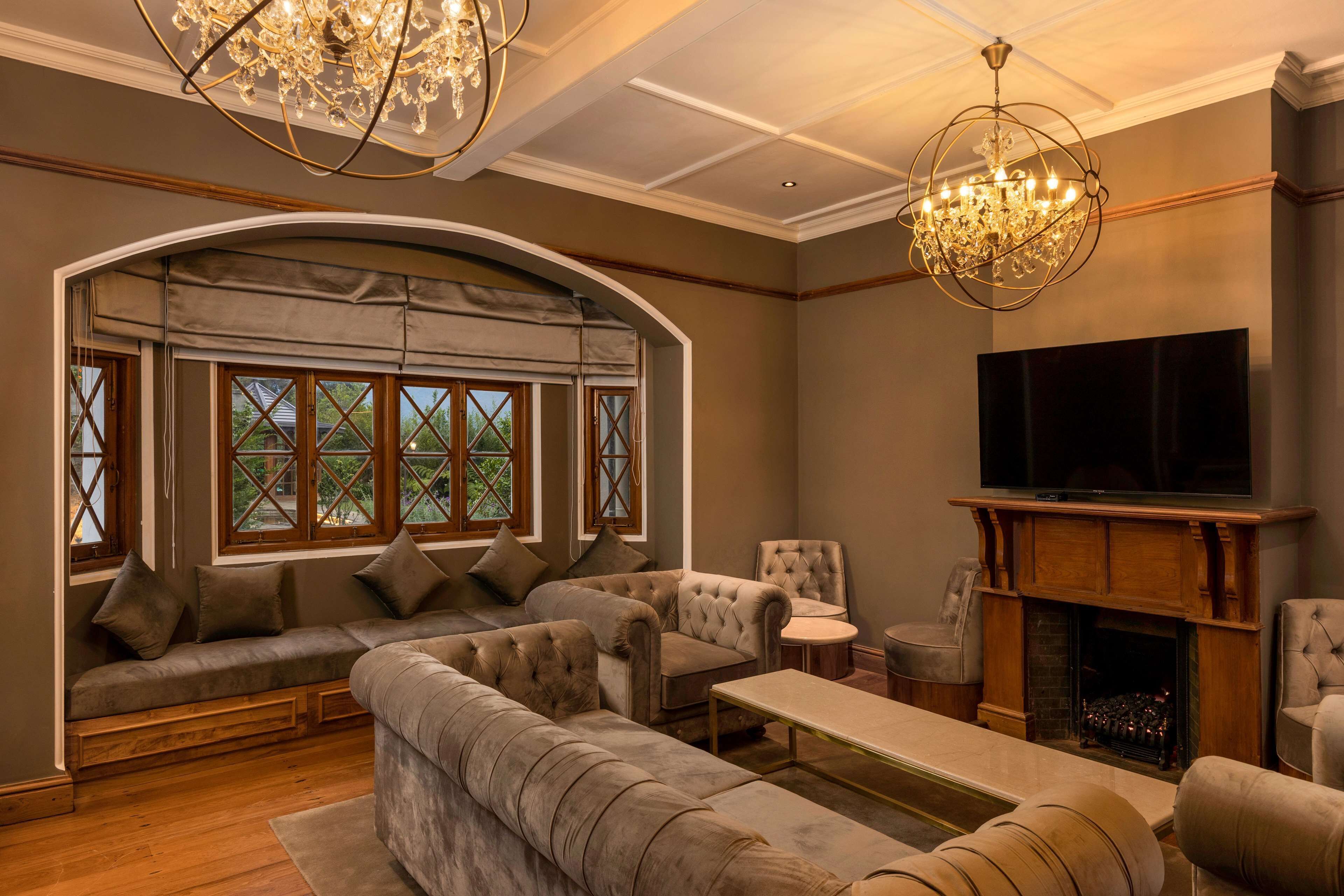 A cozy living room with a sectional sofa, armchairs, a fireplace, and a large TV.