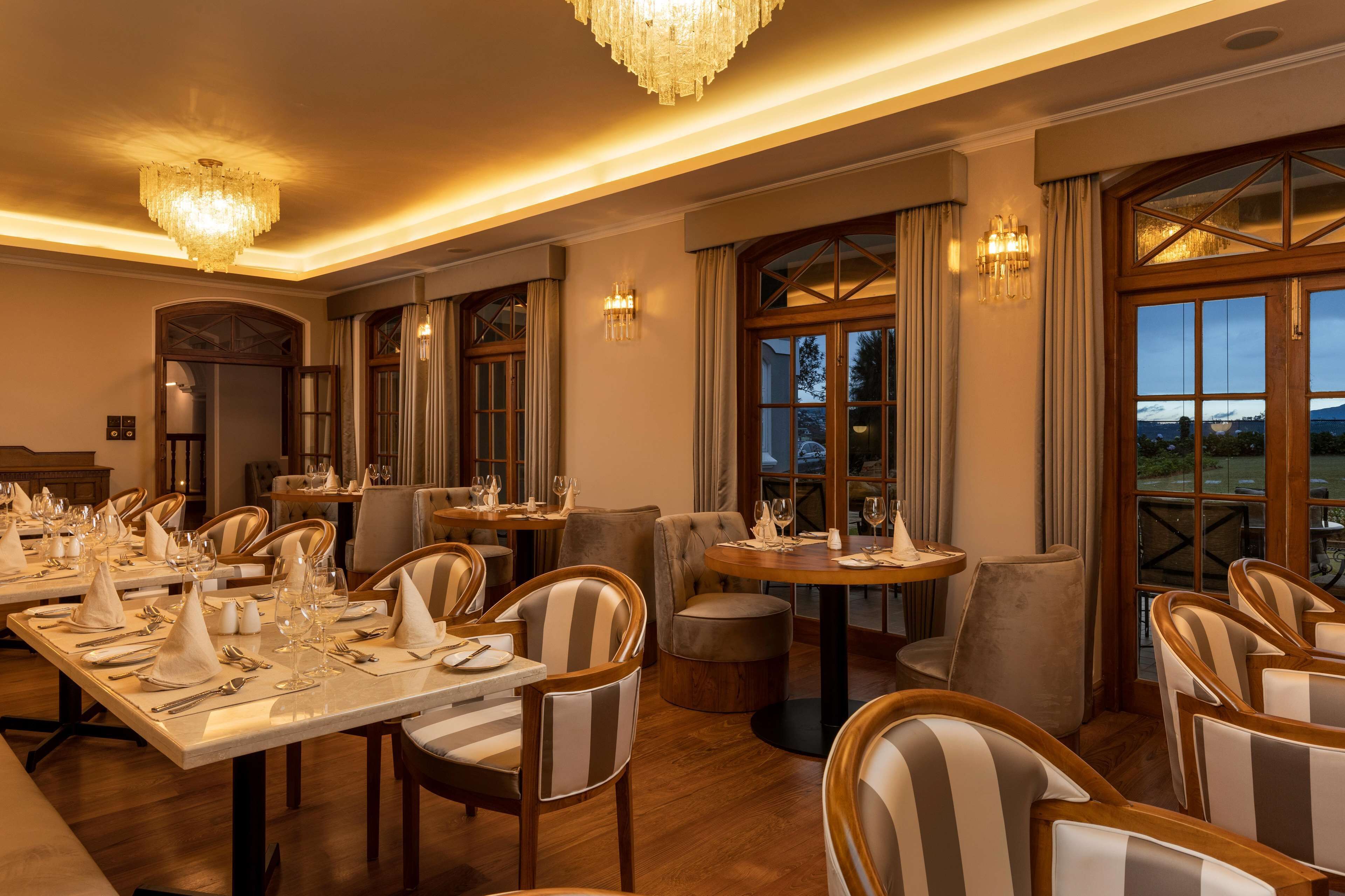 Un espace repas avec des tables dressées pour le repas, des chaises et un lustre.