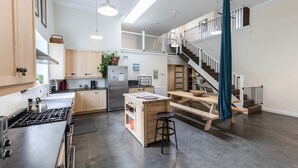 Una cocina amplia con una isla central, un comedor con banco y una escalera que sube a un nivel superior.
