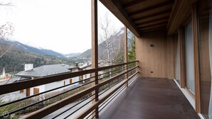 Un balcón con baranda de madera que da a un paisaje montañoso.