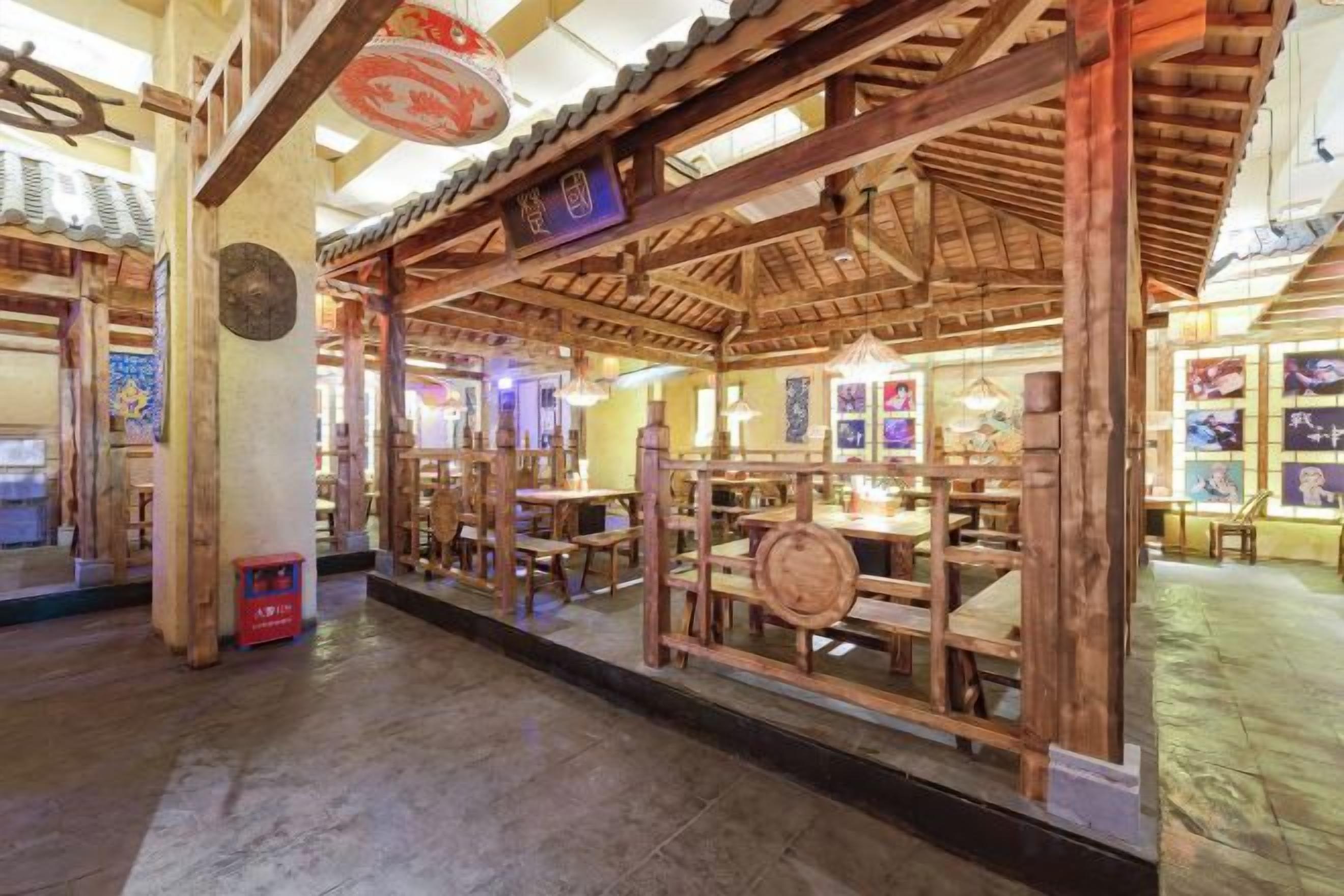 A traditional wooden structure with a thatched roof, possibly a restaurant or tea house, with tables and chairs inside.