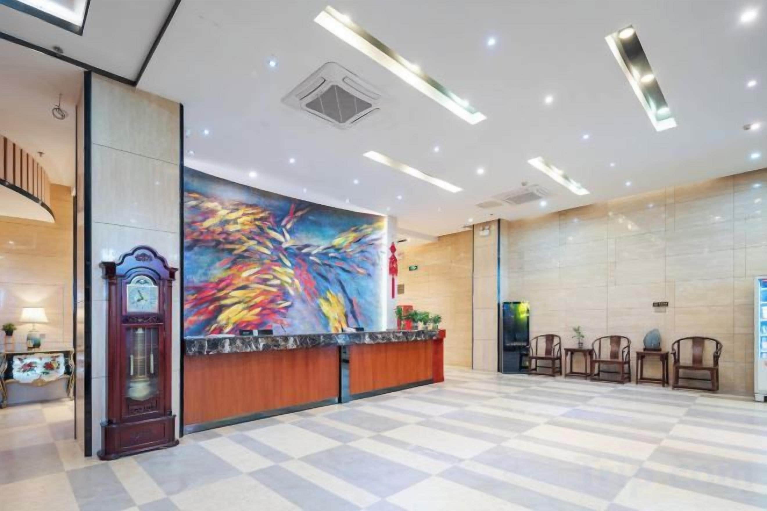 A hotel lobby with a reception desk, a large abstract painting, a clock, and a check-in counter.
