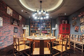 Una taula rodona amb cadires en una habitació de parets de rajola, una biblioteca i un armari vermell.