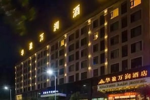 A multi-story hotel building with illuminated signage and a row of windows. - Huaying Wanrun Hotel (Cenxi)
