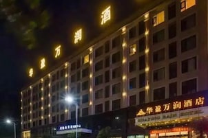 Un edificio de hotel de varios pisos con señalización iluminada y una fila de ventanas.