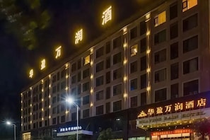 A multi-story hotel building with illuminated signage and a row of windows. - Huaying Wanrun Hotel (Cenxi)