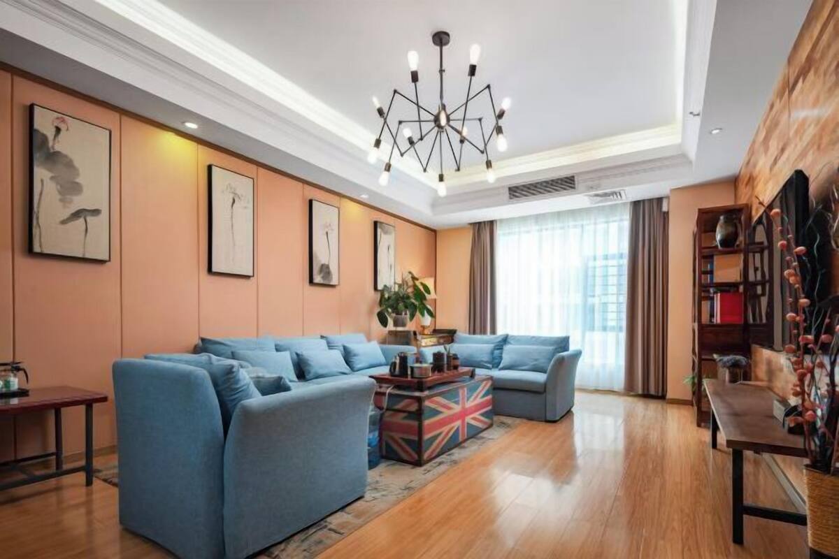 A modern living room with a sectional sofa, a decorative table, and a unique ceiling light fixture.