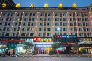 A multi-story hotel with a row of windows on each floor, a prominent entrance with signage, and a parking area in front. - Huaying Wanrun Hotel (Cenxi)