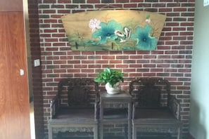 A brick wall with a floral artwork and a small table with a plant. - Huaying Wanrun Hotel (Cenxi)