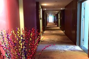 Ein Hotelkorridor mit einer Zierpflanze, einem Marmorboden und Blick auf die Lobby.