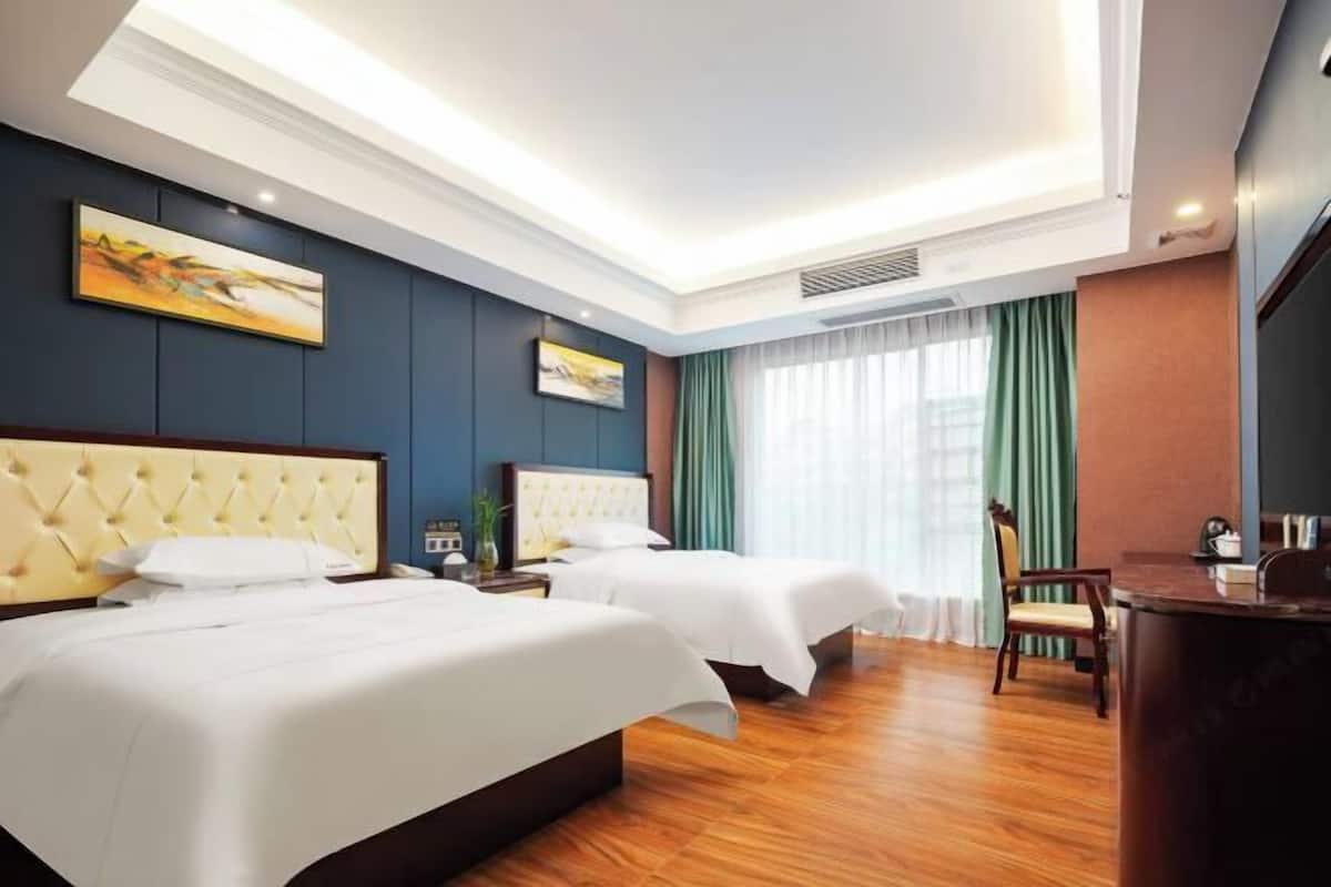 A hotel room with two beds, a desk, and a chair.