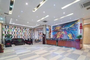 Zona de recepción de un hotel con suelo a cuadros, un mostrador de recepción, un cuadro abstracto de colores y una pared con diseño vertical.
