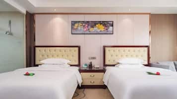 Habitación de hotel con dos camas, una mesita de noche con lámpara, un cuadro en la pared y suelo alfombrado.