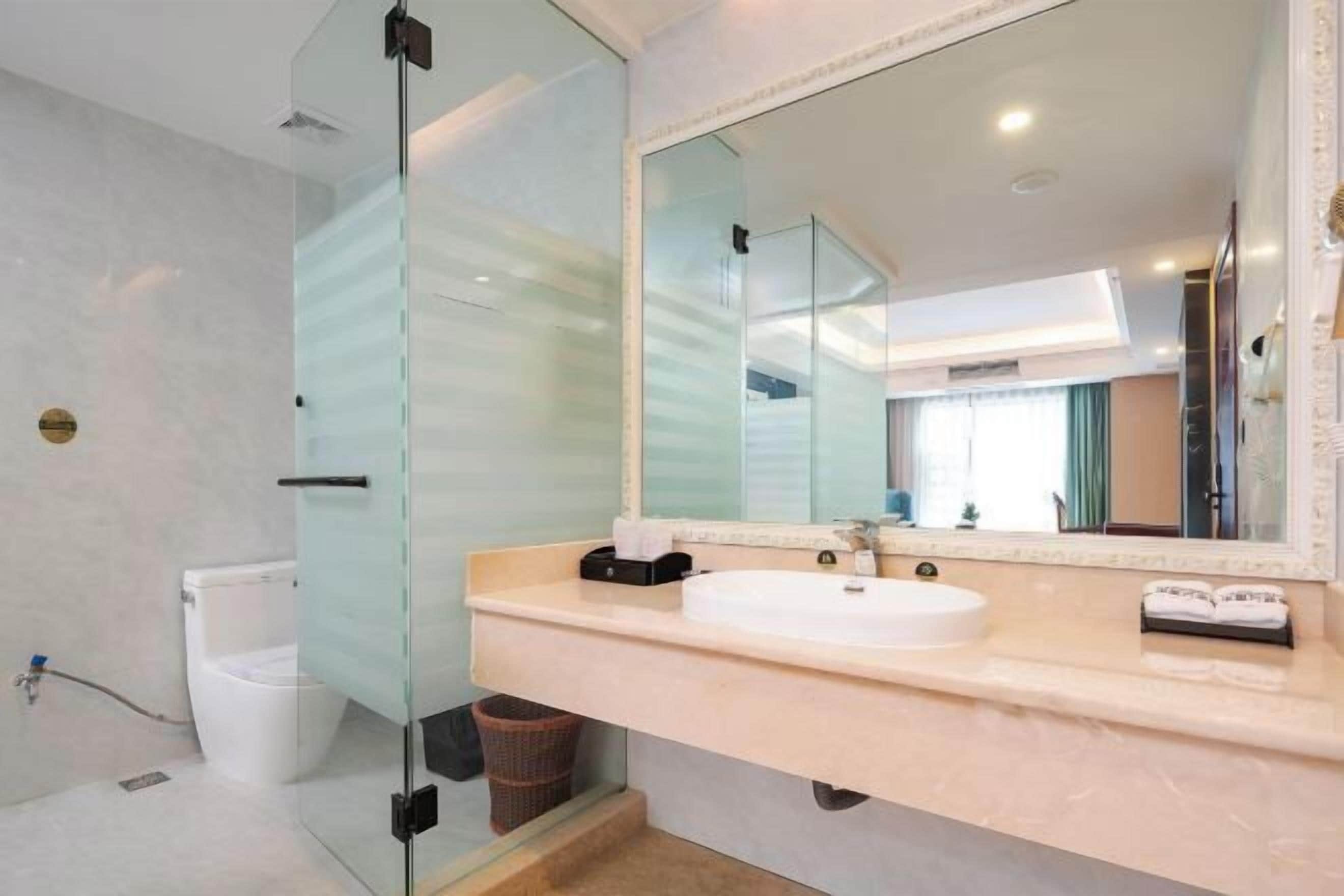 A modern bathroom with a glass shower enclosure, a white sink, and a large mirror.