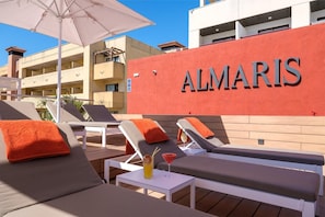 A rooftop lounge area with sun loungers, a table with a drink, and a building with 'ALMARIS' signage. - Estival Park Almaris (Vila-Seca)