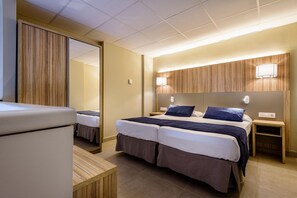 Habitación de hotel con cama doble, mesitas de noche, un espejo y un panel de pared de madera.