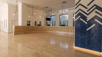 Un vestíbulo amplio con mostrador de recepción de madera, iluminación colgante moderna y un revestimiento de pared con motivo de espiga.