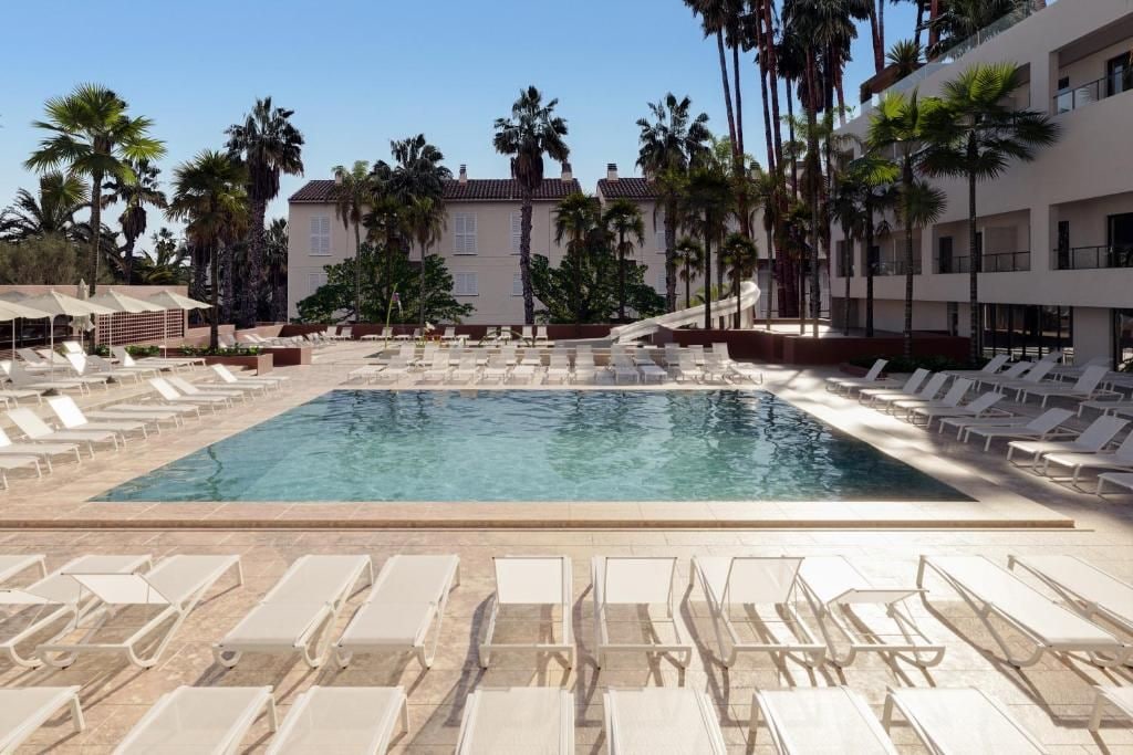 A swimming pool with lounge chairs and palm trees.