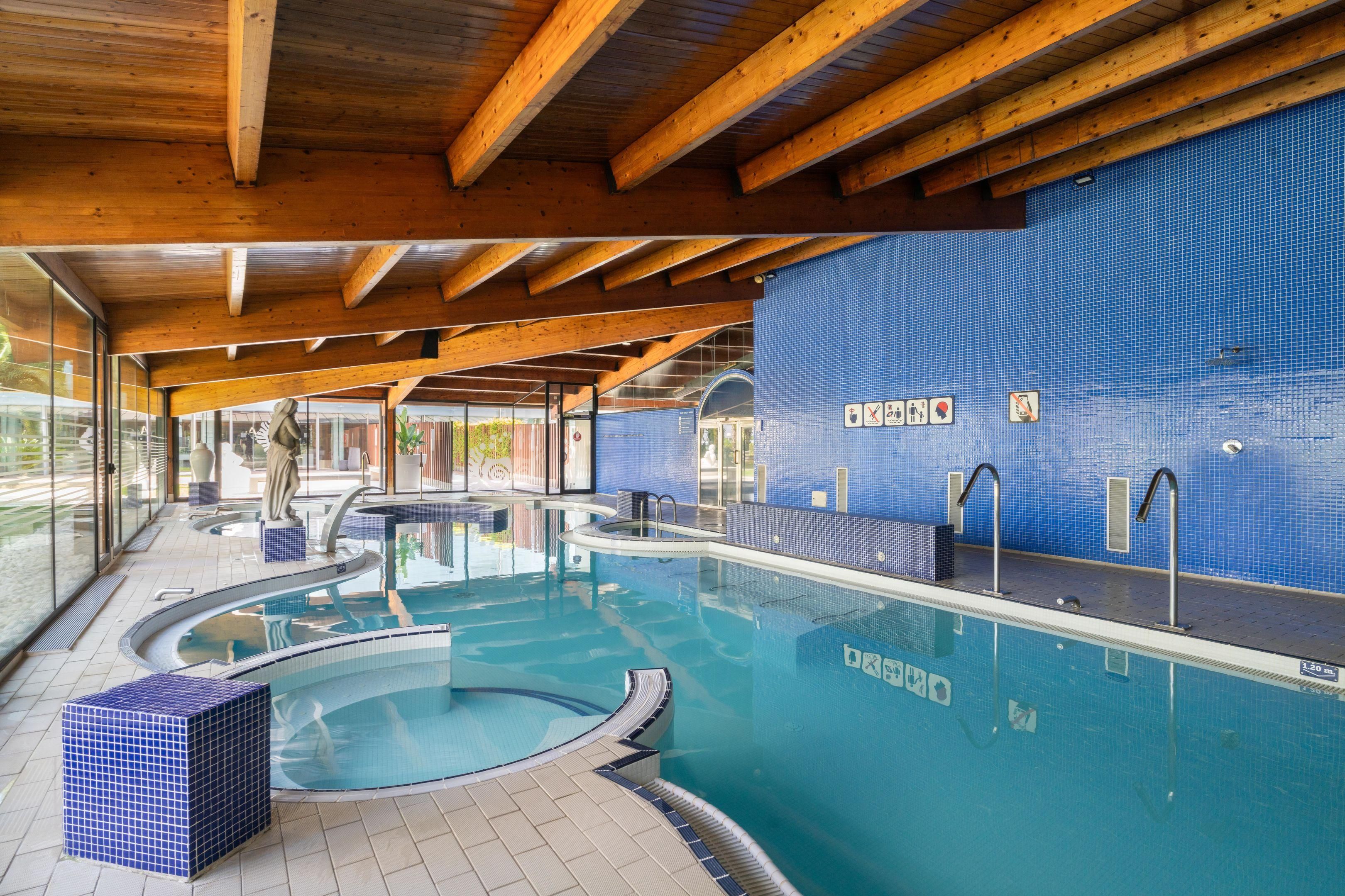 An indoor swimming pool with wooden beams, tiled walls, and clear signage.