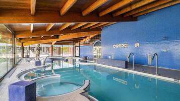 An indoor swimming pool with wooden beams, tiled walls, and clear signage.