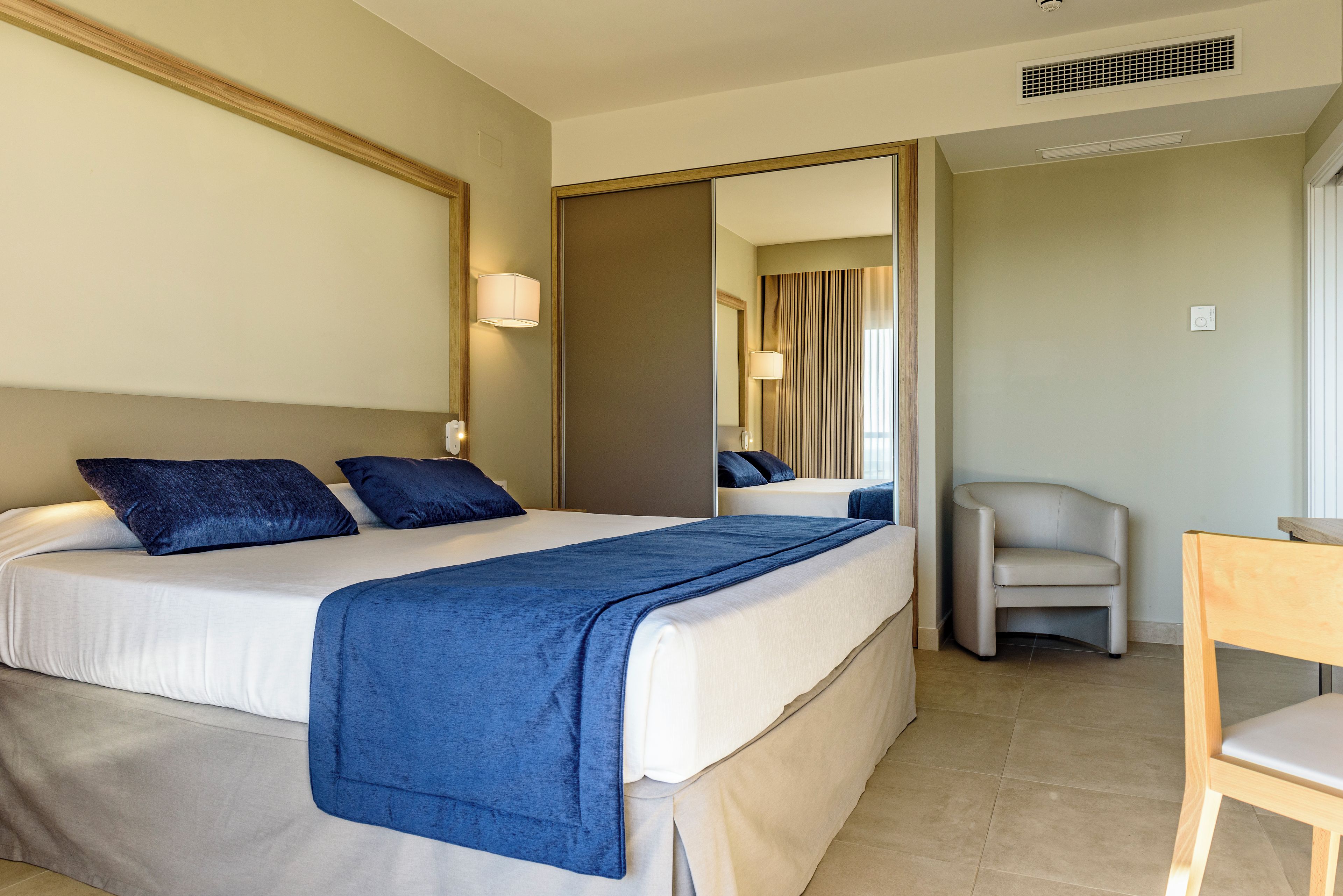 A hotel room with a bed, a chair, and a desk.