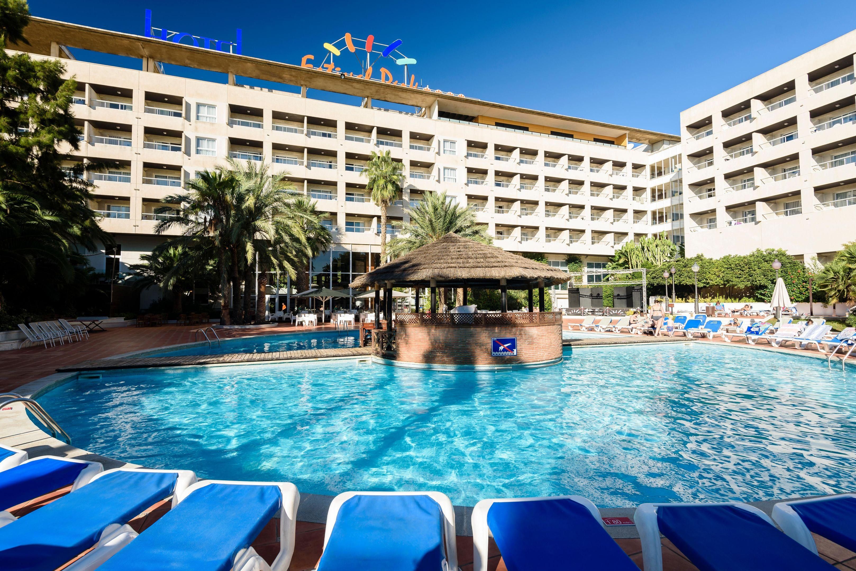 Un hotel con un amplio área de piscina, varios balcones y un pabellón central.