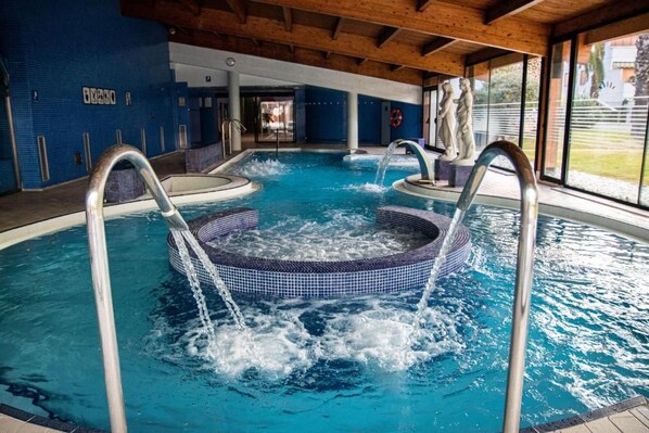 An indoor swimming pool with multiple hot tubs and clear water.