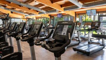 Un gimnasio con cintas de correr, bicicletas estáticas y una variedad de equipos de ejercicio.