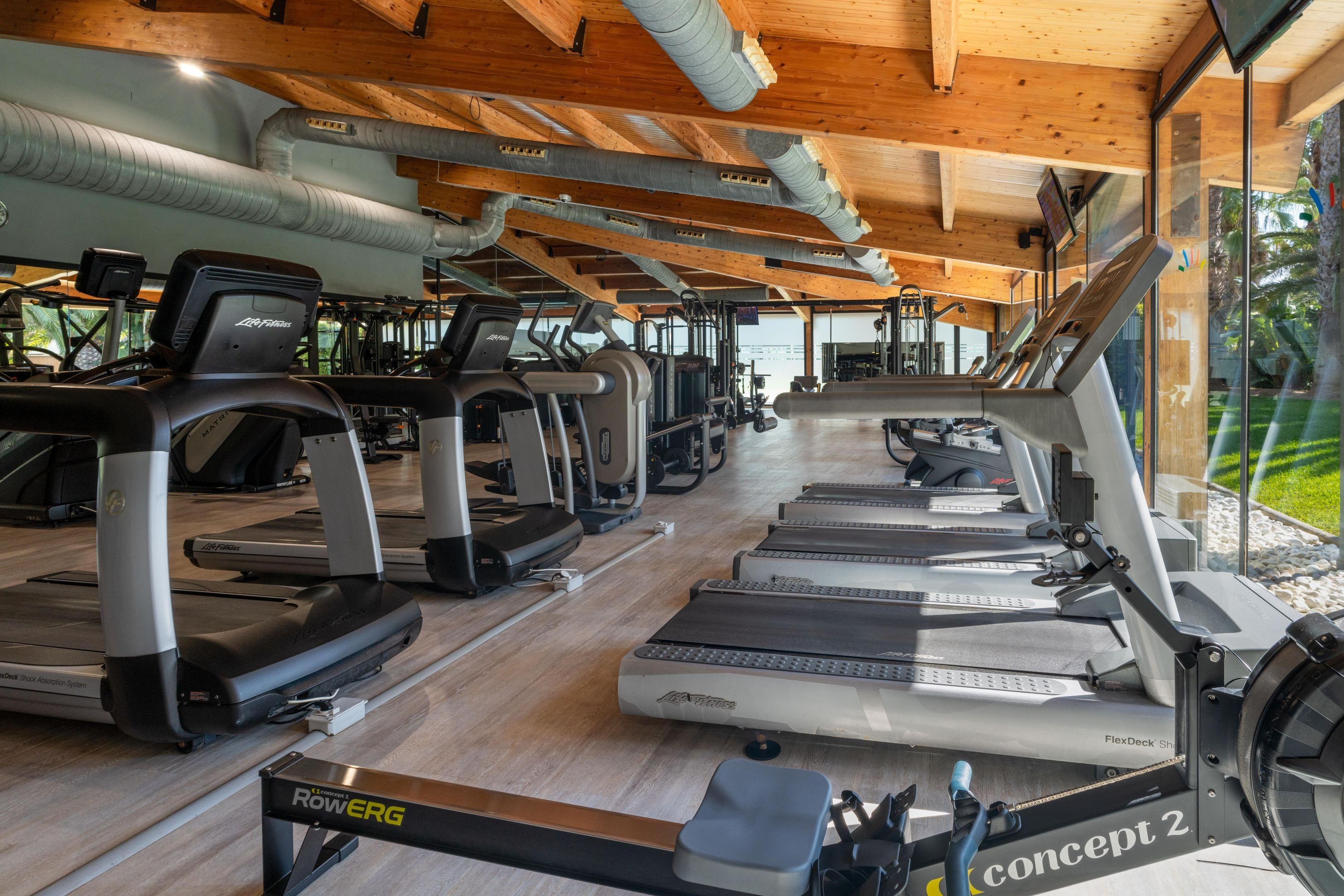A gym with multiple treadmills, stationary bikes, and rowing machines.