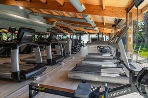 Un gimnasio con cintas de correr, bicicletas estáticas y máquinas de remo.