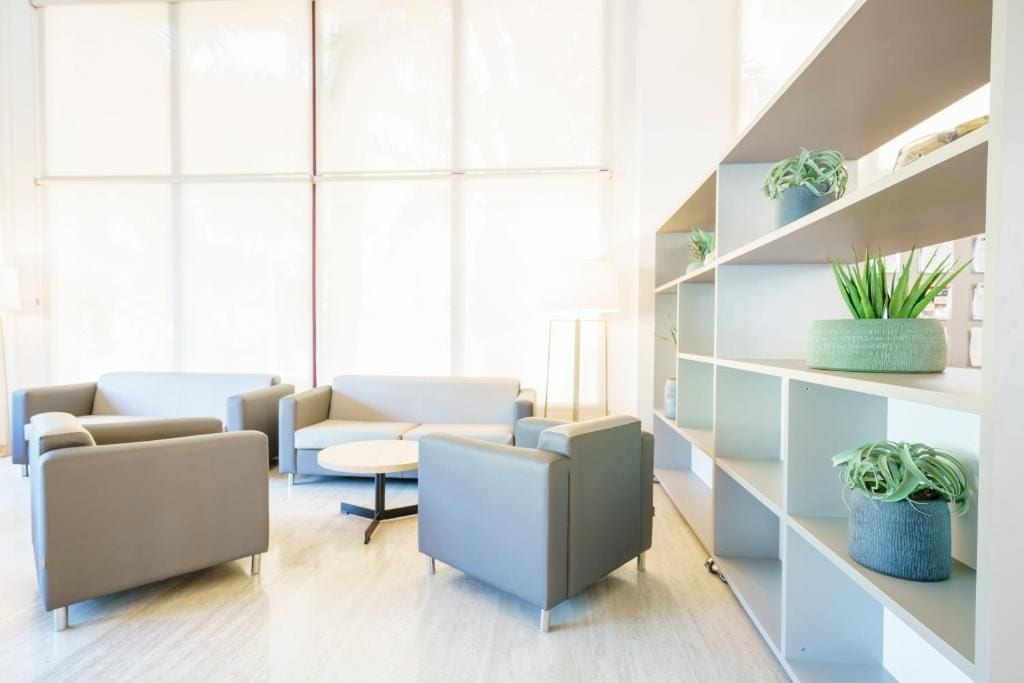 A modern interior with a sectional sofa, a small round table, and built-in shelving with plants.