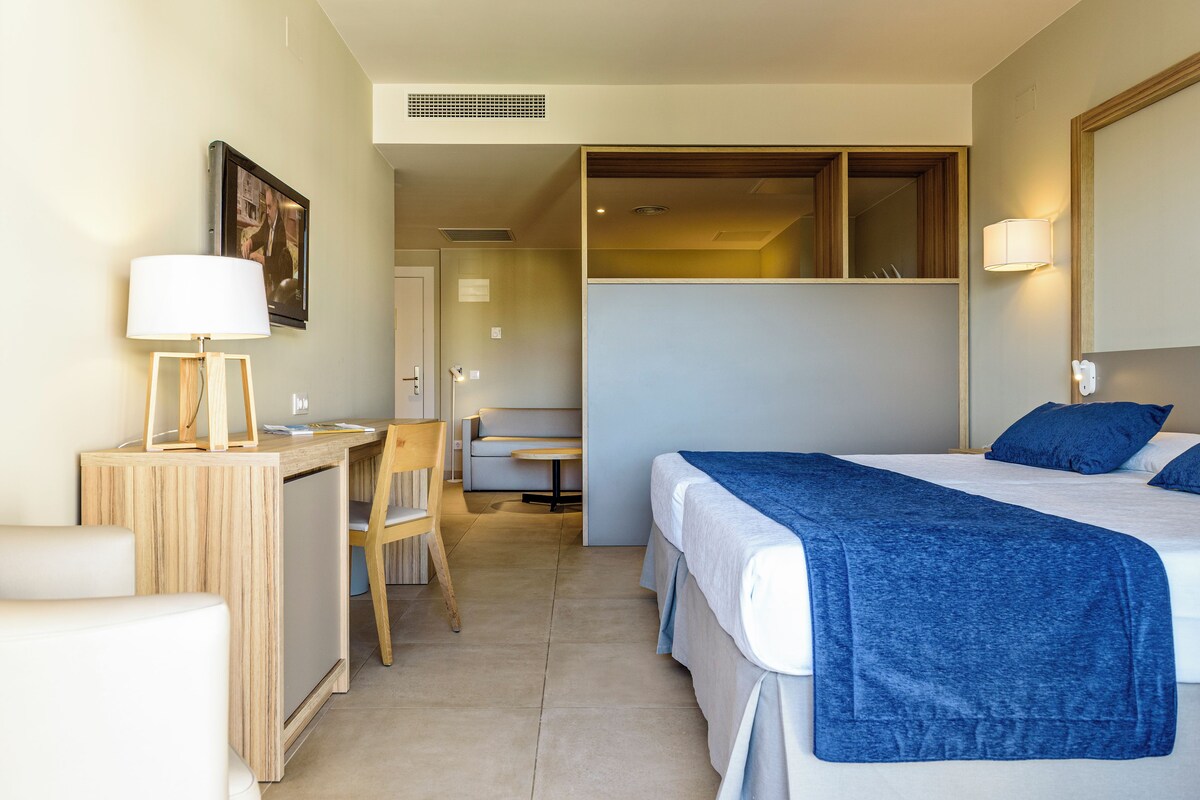 Una habitación de hotel con cama, escritorio, silla y una pequeña mesa.