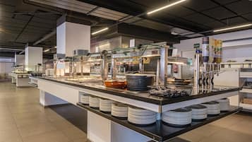 A buffet setup with multiple food stations, a glass display case, and a digital clock.