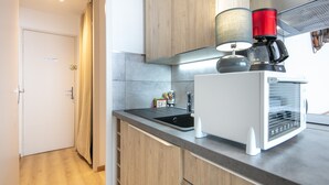 A modern kitchen with wooden cabinets, a black sink, and a coffee machine.