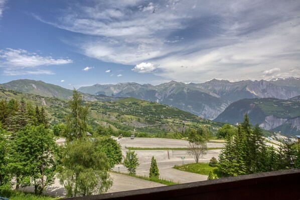 A mountainous landscape with a clear sky and a parking area in the foreground.