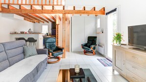Una sala de estar moderna con un sofá, dos sillones de cuero, una mesa de centro y un televisor sobre un mueble de madera.