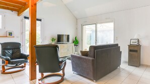 Una sala de estar con un sofá, dos mecedoras, un televisor y un aparador.