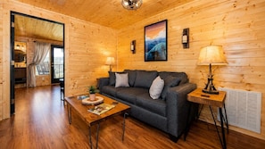A cozy wooden interior with a sofa, a table with a plant, and a lamp. - Mountain Views at Dolly's Castle Unit 5 (Sevierville)