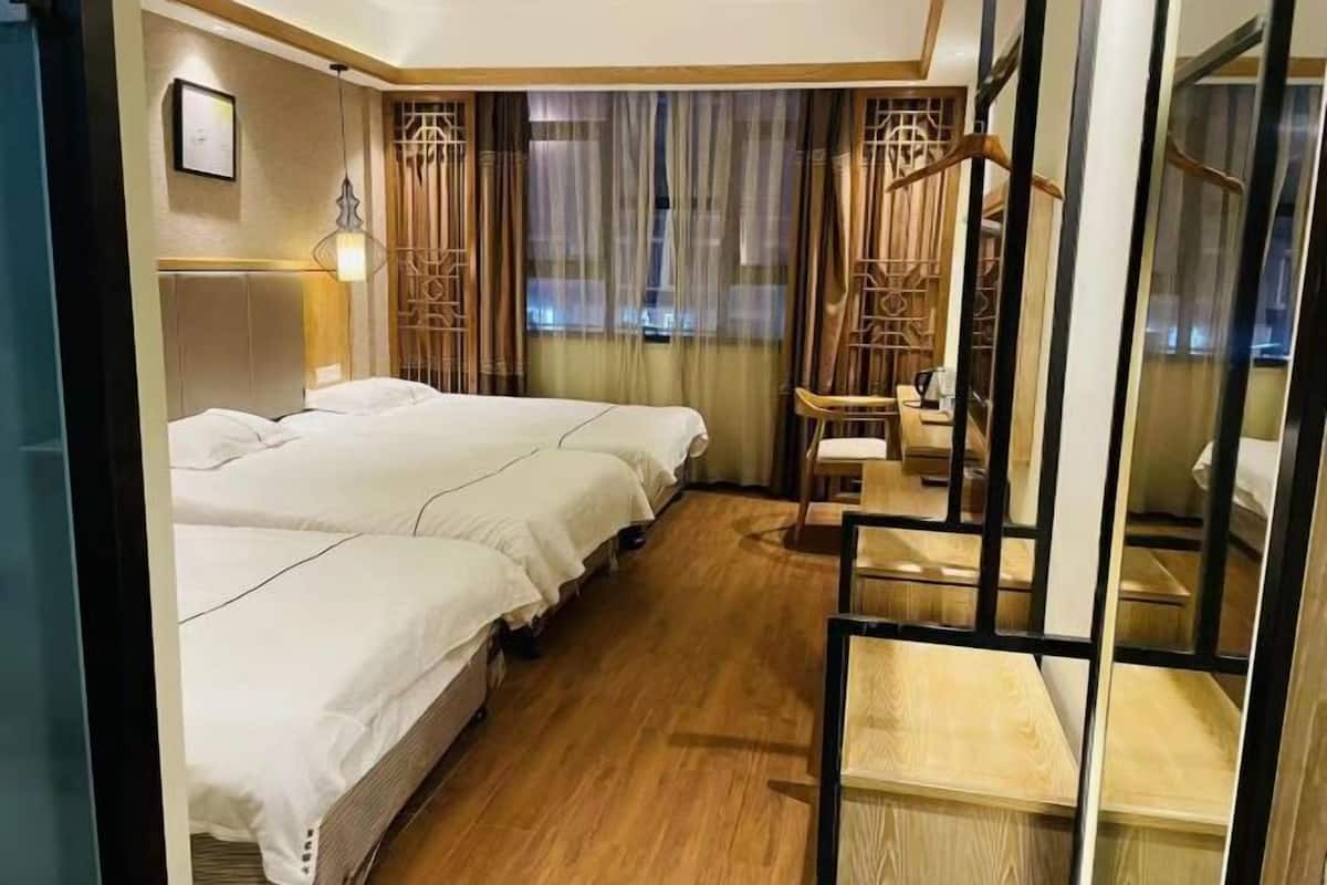 Une chambre d’hôtel avec deux lits, un bureau, une chaise et une vue par la fenêtre, qui est dotée de rideaux.