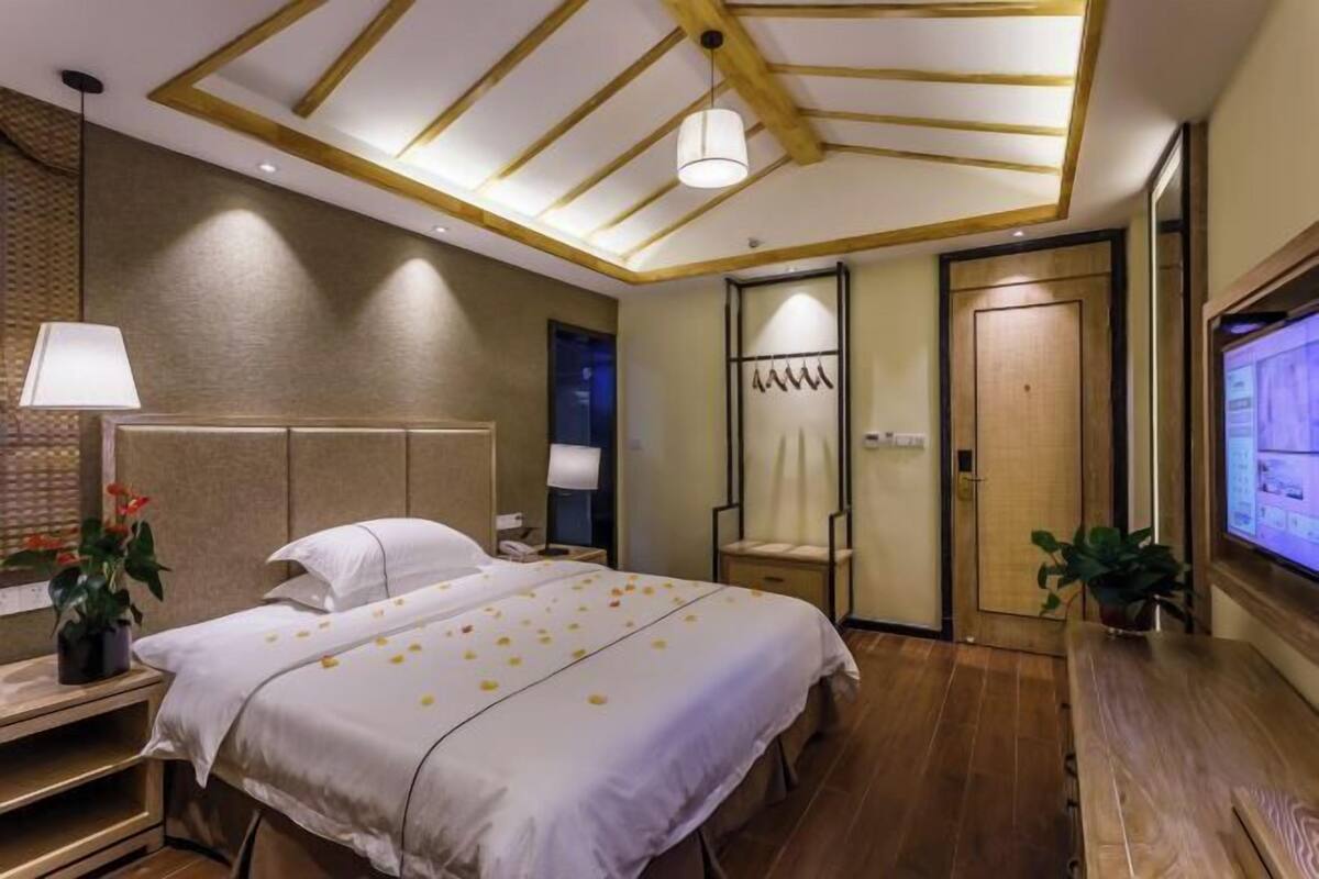 Une chambre d’hôtel avec un lit, une table de chevet, une lampe et un écran de télévision.