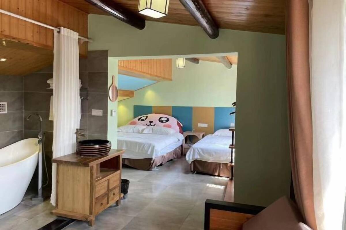 Une chambre dotée d’une baignoire, d’un meuble-lavabo en bois et de deux lits avec des têtes de lit colorées.