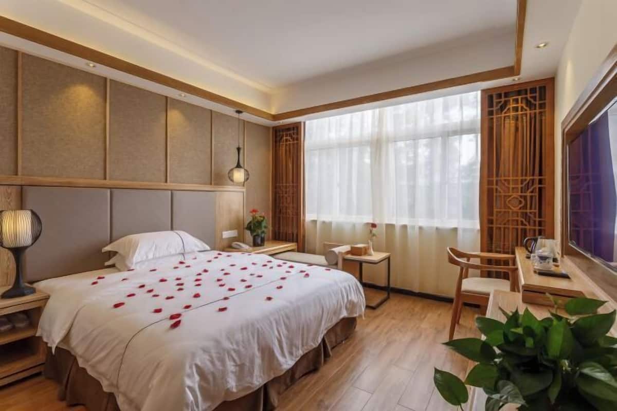 Une chambre d’hôtel avec un grand lit, des tables de chevet, un bureau et une chaise.