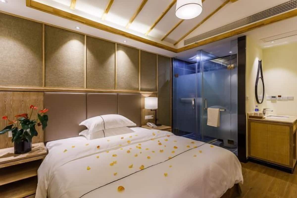 Une chambre d’hôtel équipée d’un lit, d’une table de chevet, d’une lampe et d’un espace douche.