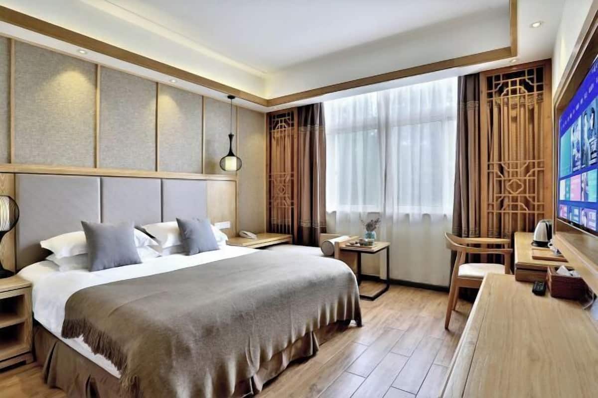 Une chambre d’hôtel avec un grand lit, des tables de chevet, un bureau et une télévision.