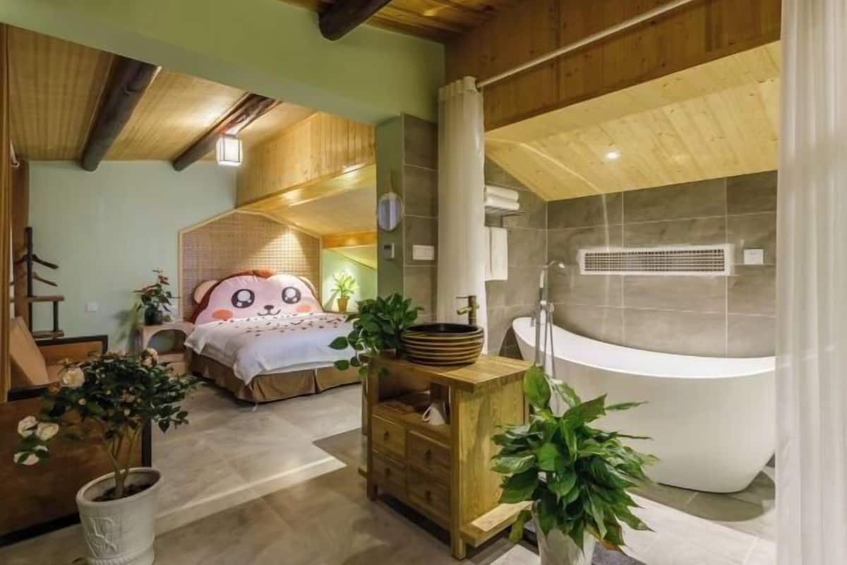 Une chambre avec un grand lit, une table de chevet en bois et une salle de bain équipée d’une baignoire et d’une douche.