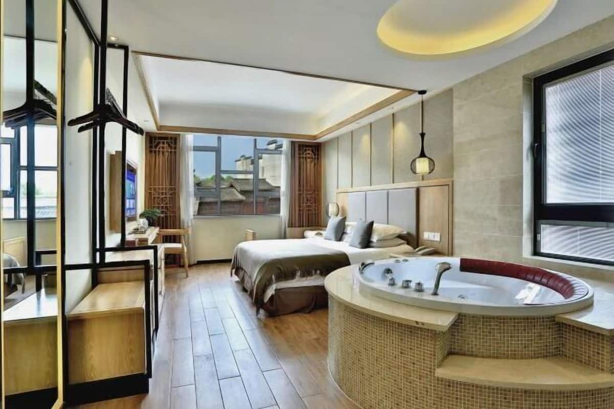 Une chambre d’hôtel moderne avec un grand lit, une baignoire à formes arrondies et une vue sur la ville.