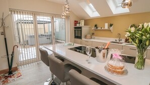 A modern kitchen with a central island, bar stools, a wine cooler, and a vase with flowers. - Garthgate Holiday Lodge (Malton)