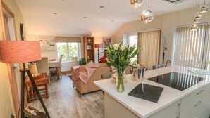 A modern kitchen with a central island, a dining area with a table and chairs, and a living room with a sofa. - Garthgate Holiday Lodge (Malton)