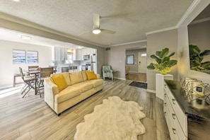 A spacious living room with a beige sofa, a white shag rug, and a ceiling fan. - The Harold House (Olathe)