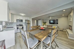 A modern kitchen with white cabinets, stainless steel appliances, and a wooden dining table with chairs. - The Harold House (Olathe)